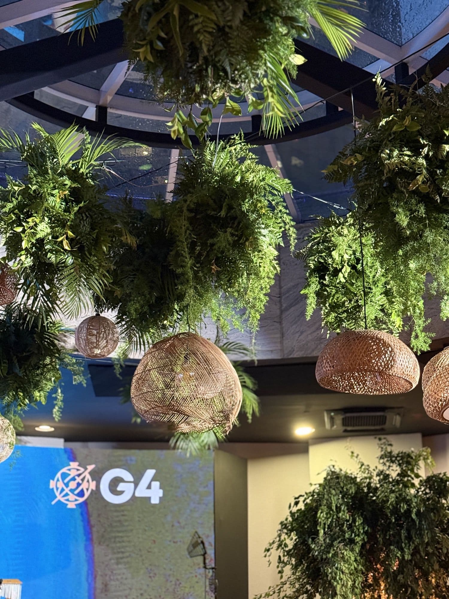 Cenografia com folhagem suspensa e iluminação em rattan